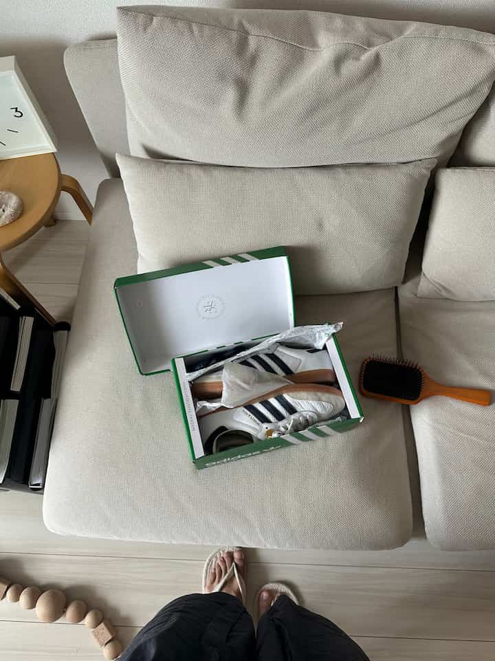 Natural tone living room with beige sofa featuring a shoe box with sneakers, complemented by light wood flooring and side table