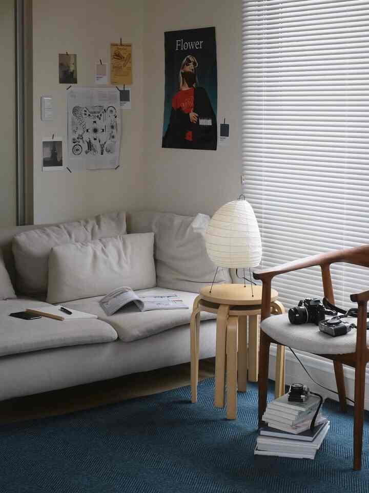 Living room in white and navy tones featuring beige sofa, wooden armchair, and navy rug creating a cozy atmosphere