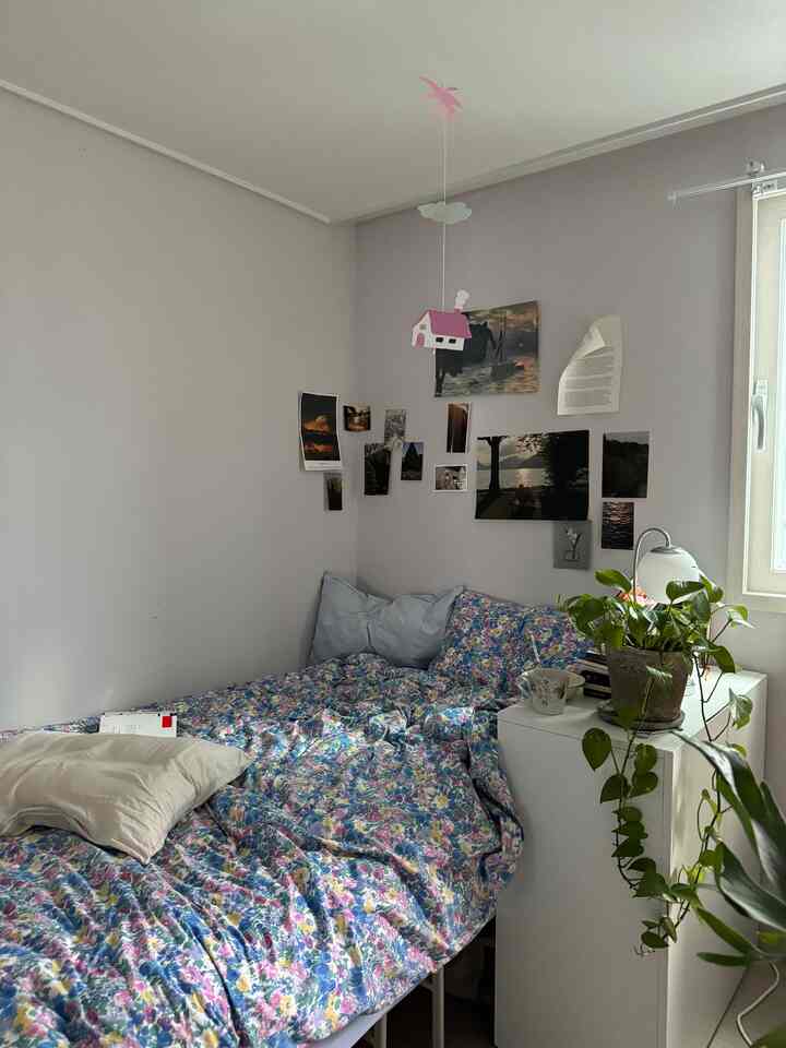 パステルカラーの6畳寝室、シングルベッドとナイトテーブル、植物が配置された落ち着いた空間