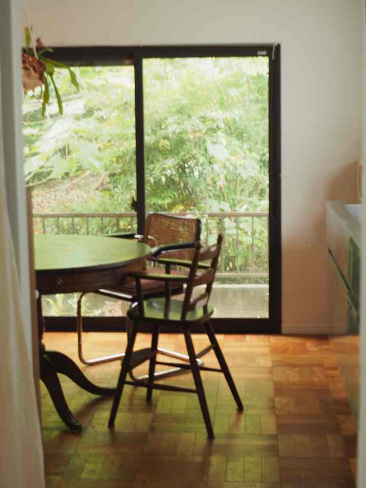 Warm wood tone dining room with large window allowing natural light, vintage Mid-Century Modern style space