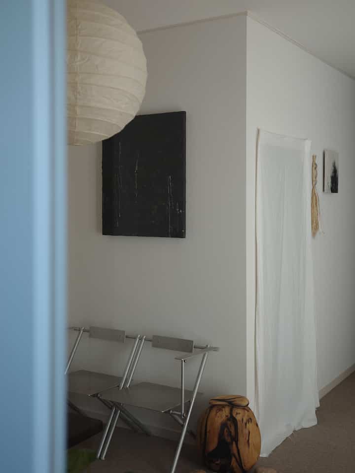 白とナチュラルカラーの空間、金属製折りたたみ椅子と木製アクセサリーが置かれた雰囲気のあるインテリア