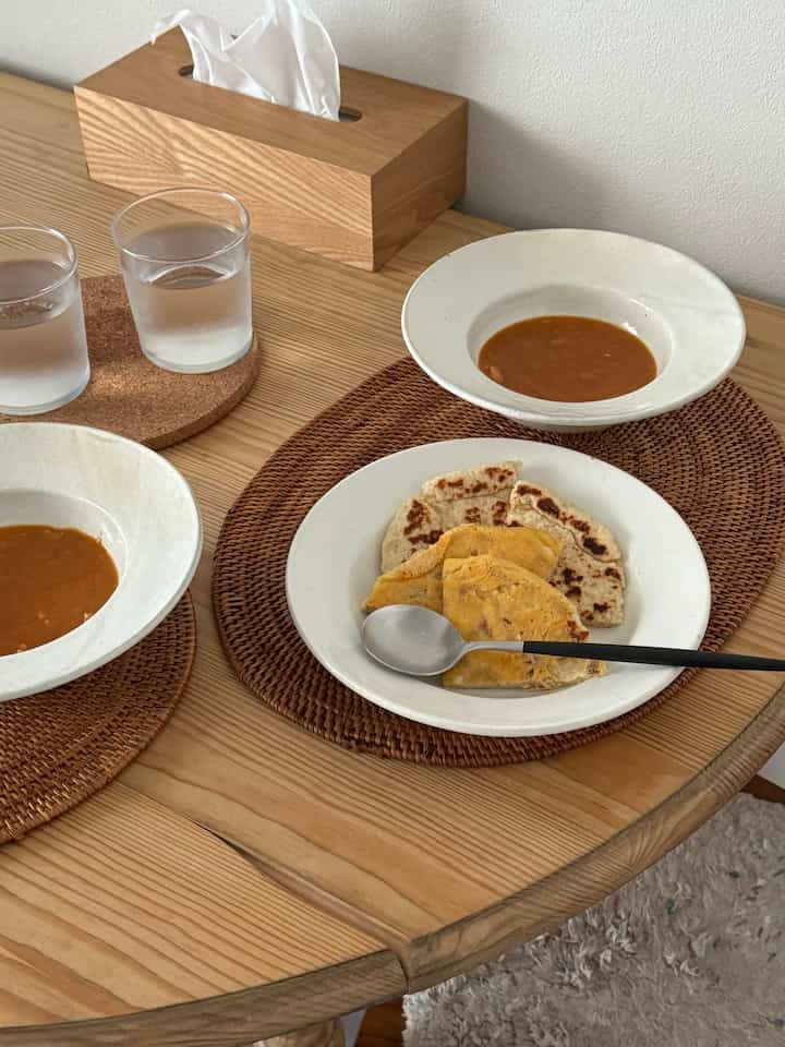 ナチュラルなブラウン色調の1LDKダイニング、テーブルに皿とグラスが置かれた落ち着いた食事の空間