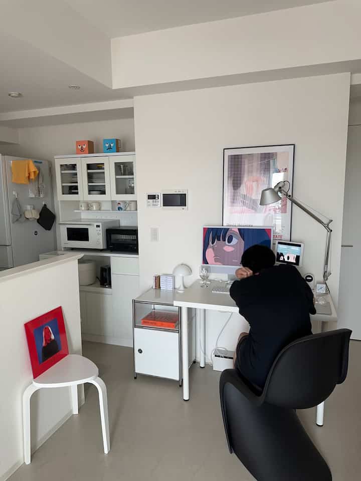 白と黒のトーンのワンルームホームオフィス、白いデスクと黒いパントンチェアが配置されたシンプルでモダンな空間