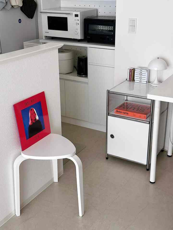 白を基調としたキッチン兼ワークスペース、シンプルな家具と家電が配置された清潔感のあるインテリア