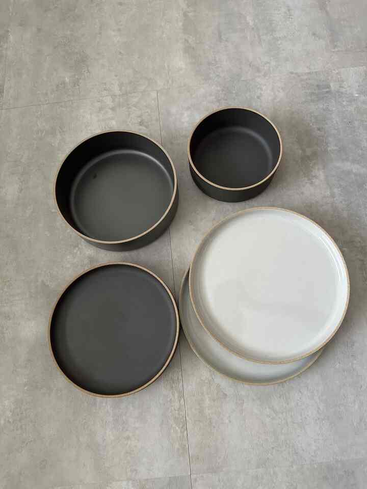 モノトーンのタイル床の上に並べられたハサミポーセリンブランドの白と黒の皿とボウル