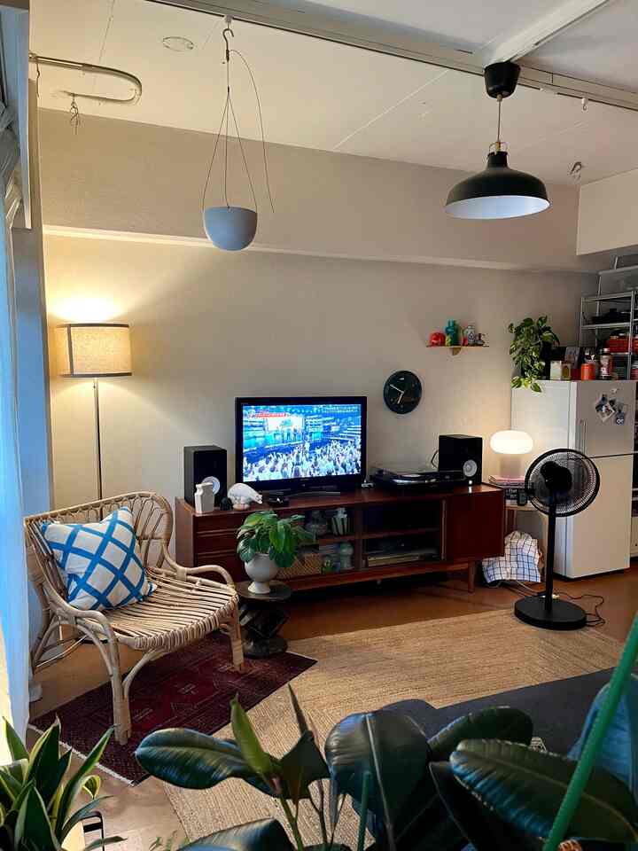 ベージュ色調のリビング、ナチュラルな家具とフロアランプ、テレビ台が配置された雰囲気のある空間