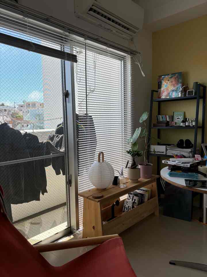 明るい黄色の壁と木製収納ベンチが配置されたバルコニーの見えるナチュラルなインテリア空間