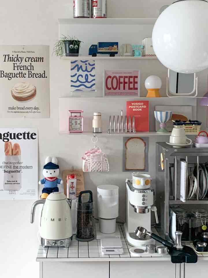 White and natural toned kitchen space featuring coffee grinder, espresso machine, and various home cafe accessories on ceramic tabletop creating cozy atmosphere