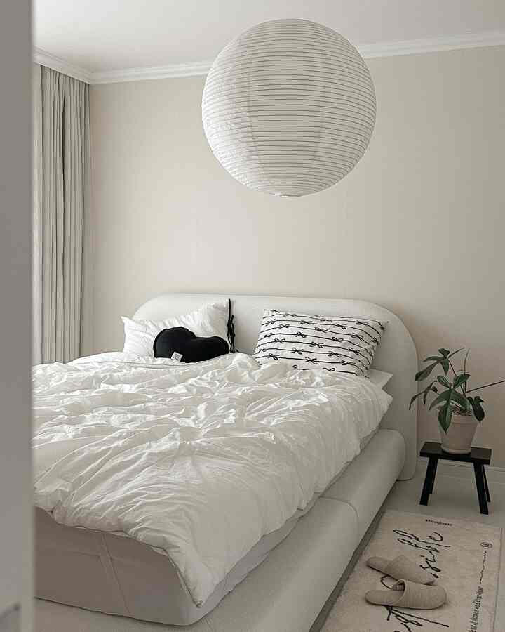 White-toned bedroom featuring a fabric bed and minimal furniture, creating a simple and cozy interior