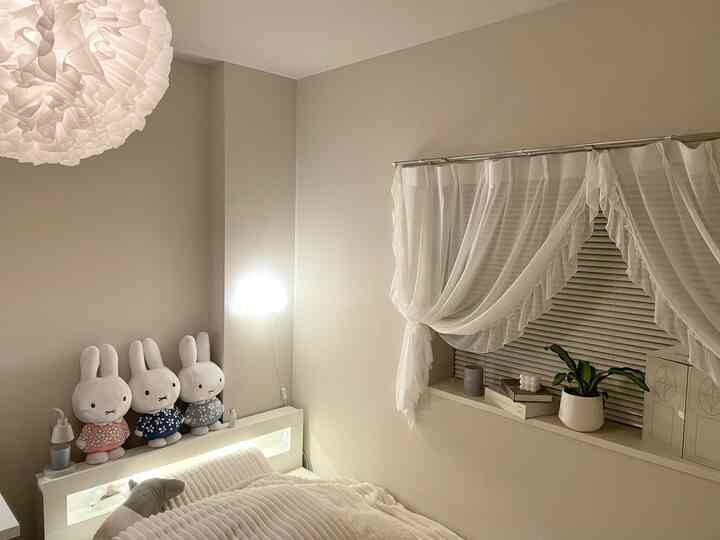 白とナチュラルカラーの寝室、柔らかなカーテンとペンダントライトが温かみのある雰囲気を演出するインテリア