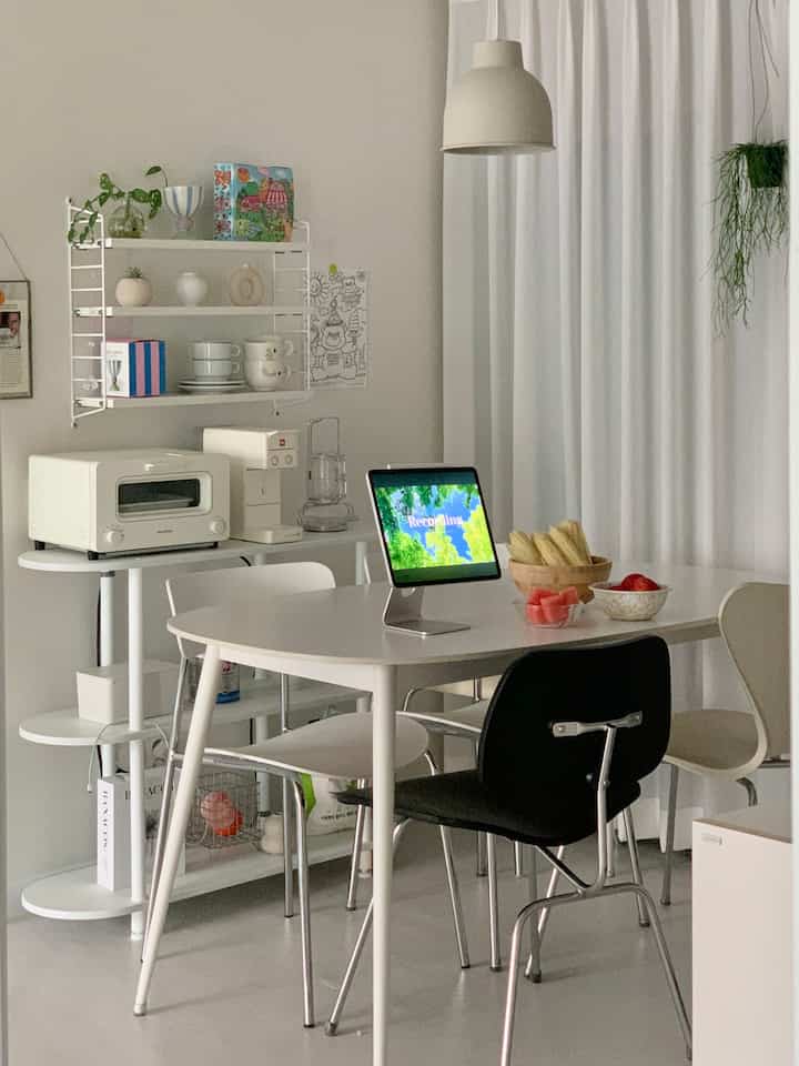 Bright white-toned kitchen space featuring a round dining table and assorted chairs with a clean modern interior