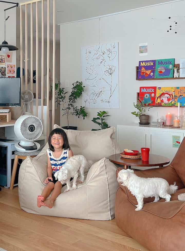 白い壁と木目調の床のリビング、ビーズクッションの上に子供と犬がいて、温かみのある居心地の良いインテリア