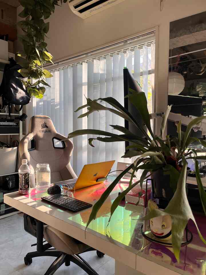 白とナチュラルトーンのコンパクトなホームオフィス、ゲーミングチェアと植物が配置された暖かな雰囲気のインテリア