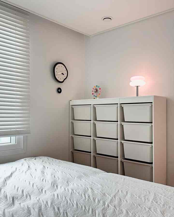 白とベージュのトーンの子供部屋、たくさんの収納ボックスと白いベッドが配置された清潔で明るい印象のインテリア
