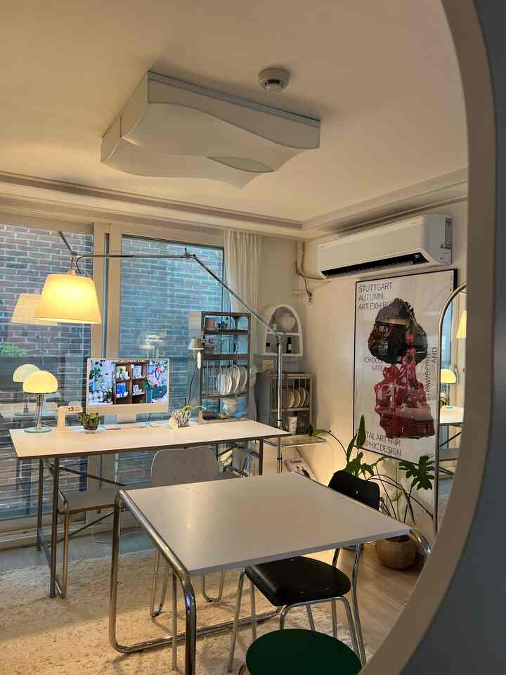 ホワイトとシルバーの色調のリビング兼ホームオフィス、ミッドセンチュリーモダン家具とフロアランプが配置されたシンプルで印象的な空間