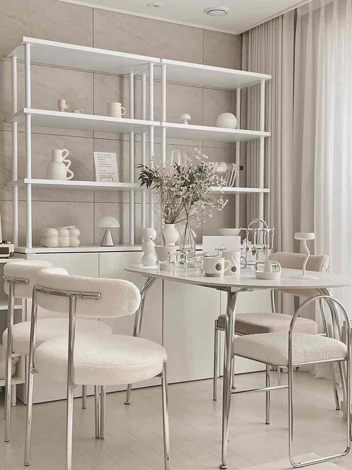 ホワイトとシルバーのトーンのダイニングルーム、セラミックのダイニングテーブルとクッションチェアが配置されたモダンで清潔感のある空間