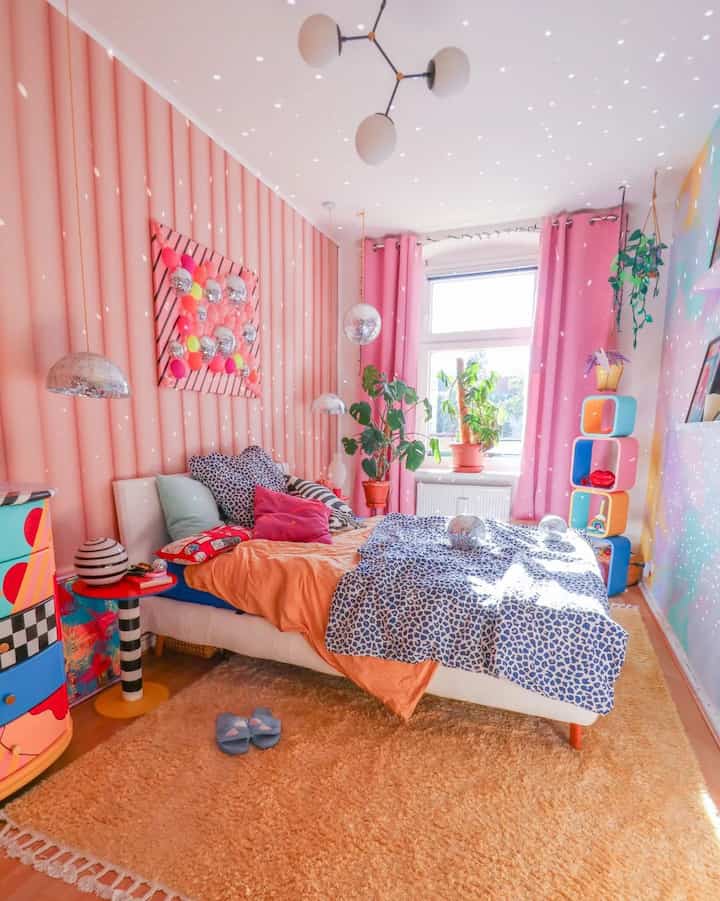 Pastel pink toned bedroom featuring a colorful bed and plants with a cute, cozy atmosphere