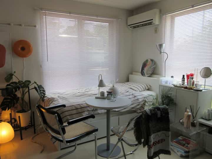 Bright white-toned bedroom featuring a striped bed, round table, and two chairs creating a cozy atmosphere