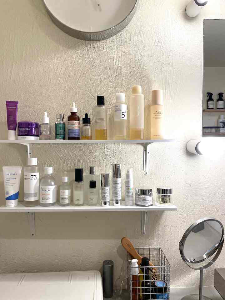 白い壁にシンプルな棚が設置され、韓国のスキンケア製品が整然と並べられた印象的なパウダールームのインテリア