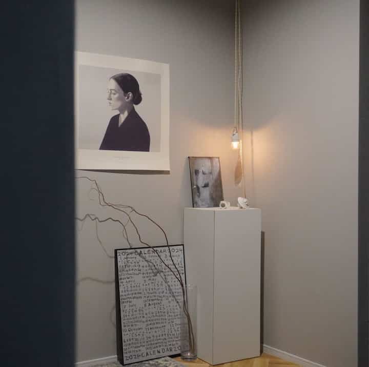 Natural gray-toned entrance featuring a minimalist pedestal and art posters in a calm composition