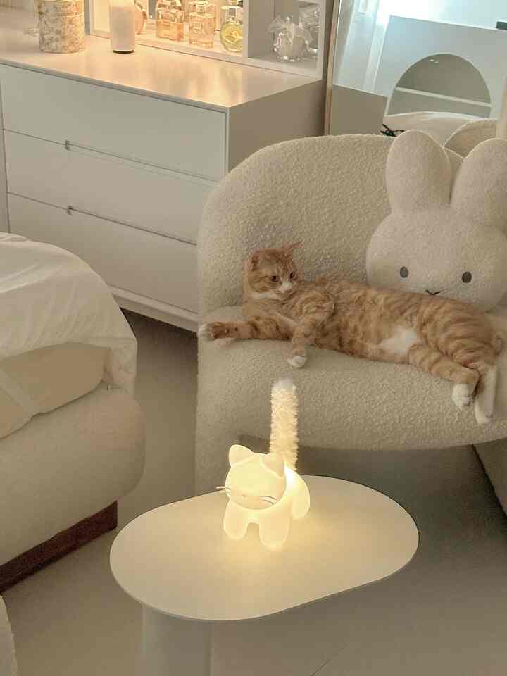 ベージュと白を基調としたリビング、アームチェアと猫がいるサイドテーブルが配置された雰囲気のある空間