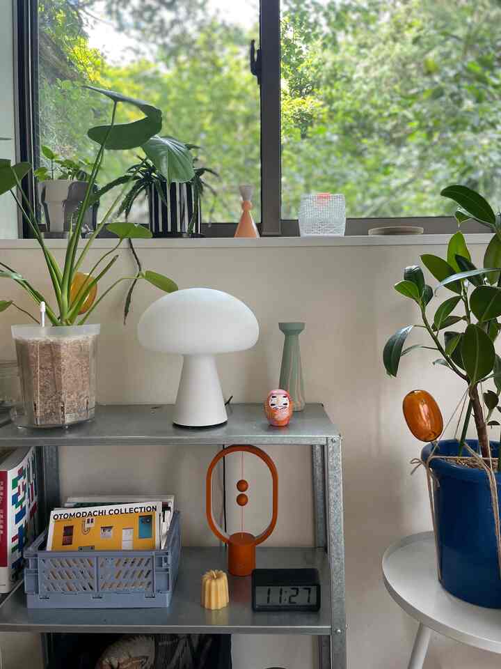 ナチュラルな色調の1Kワンルーム、棚にテーブルランプと植物が配置された雰囲気のあるインテリア