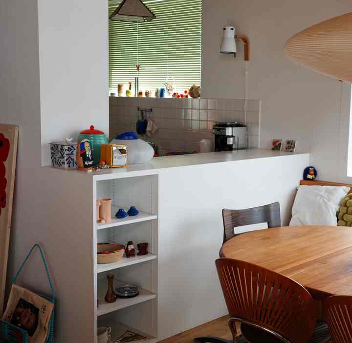 白と木目調が調和する北欧スタイルのダイニングキッチン、木製ダイニングテーブルとペンダントライトが配置された雰囲気のある空間