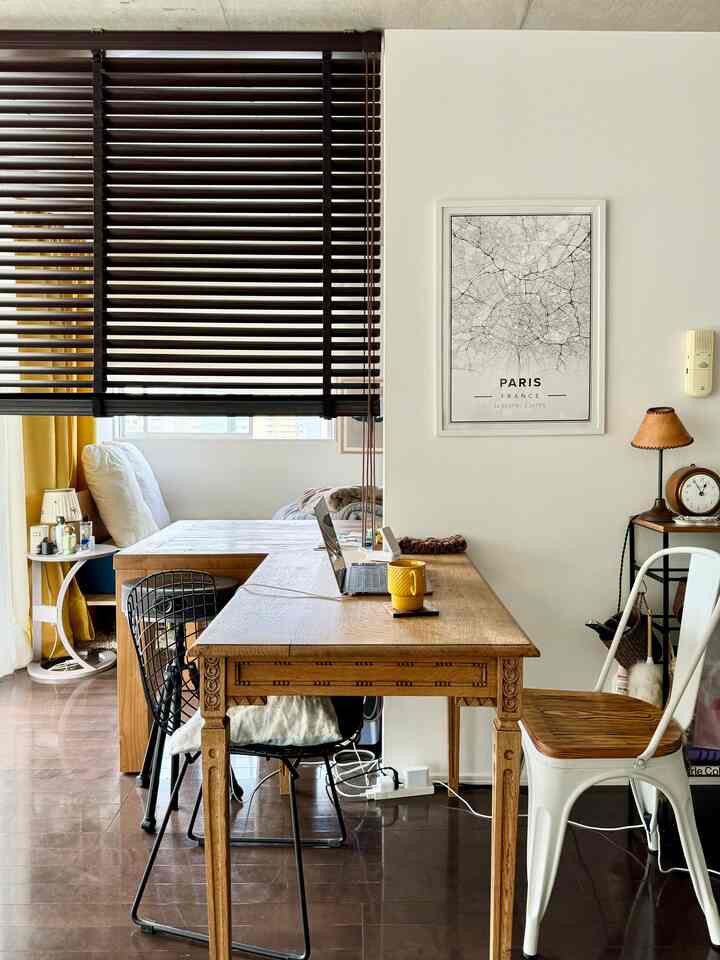 Yellow and white toned home office featuring a natural wood desk, antique furniture, and blinds creating a cozy study interior