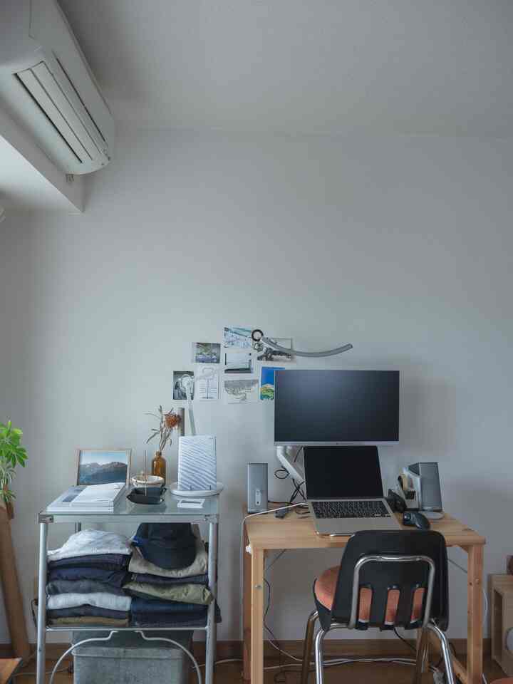 白い壁と木目調家具が配されたコンパクトな一人暮らしのホームオフィス、シンプルでミニマルなレイアウト