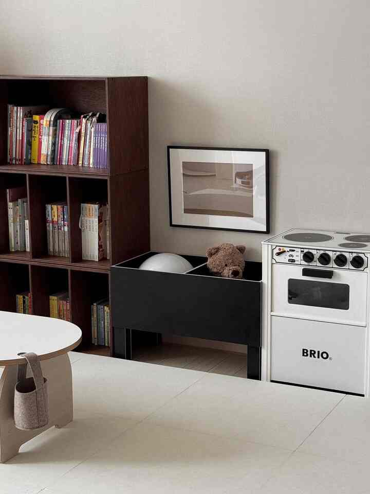 落ち着いたホワイトトーンの子供部屋、書棚とおもちゃ収納が配置された整った空間