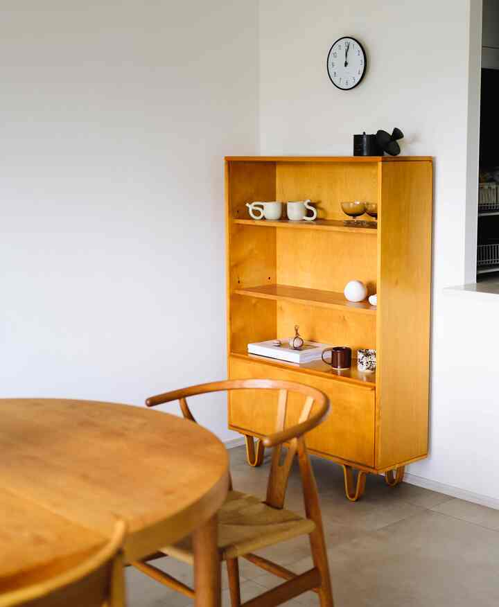 ナチュラルな木目調のダイニングルーム、木製のダイニングテーブルとYチェア、キャビネットが配置されたシンプルな空間