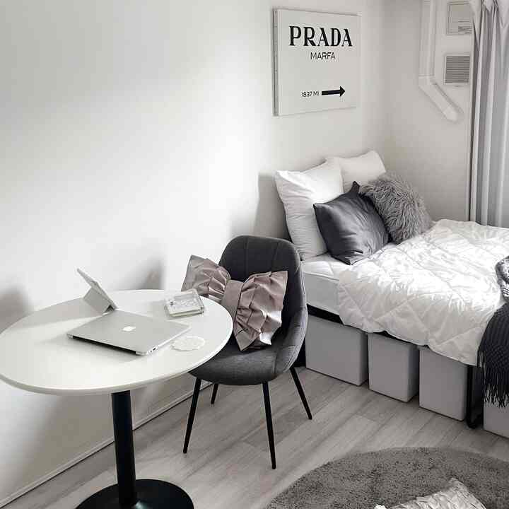 白とグレーのトーンの一人暮らし寝室、シンプルなダイニングテーブルと椅子が配置されたモダンな空間