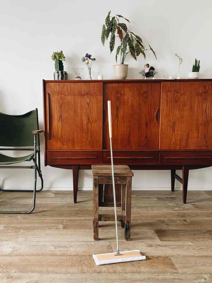 Natural wood-tone living room featuring wooden sideboard, rustic stool, and green folding armchair with a clean, warm atmosphere