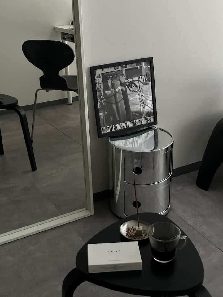 Monotone living room featuring black furniture, stools, and a large mirror arranged in a minimalistic space