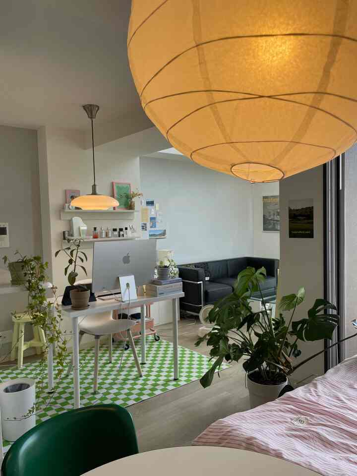 A white and natural-tone studio apartment featuring a desk, sofa, and dining table in a neat modern interior