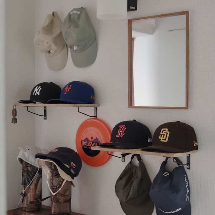 ナチュラルブラウンの色調の玄関、壁に取り付けられた簡易DIYの棚にカジュアルなキャップがきれいに収納された雰囲気のあるインテリア