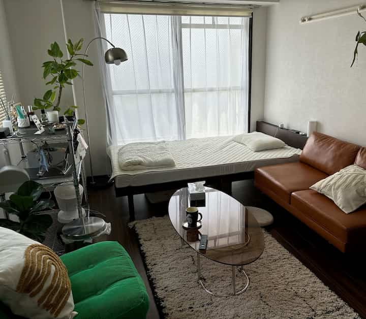 Small single household living and bedroom space featuring a brown sofa and white bedding