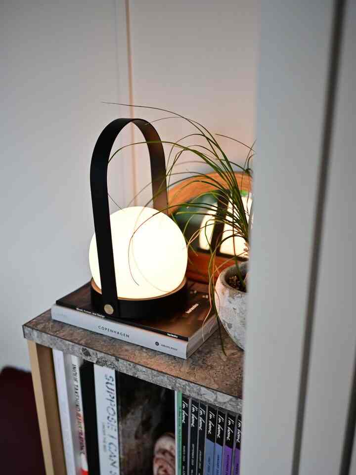 ベージュトーンのコーナー収納、無印良品のパルプボードボックスと丸いテーブルランプ、植物が配置された雰囲気のあるインテリア