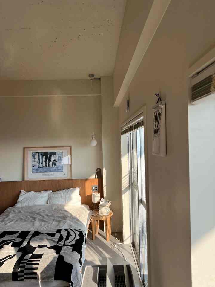 A bedroom with soft white and wood tones, natural light streaming in creates a cozy atmosphere.