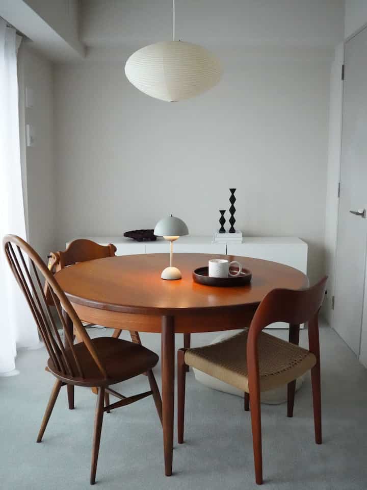 白い壁と木目調の丸いダイニングテーブルと椅子が配置されたシンプルなダイニング空間