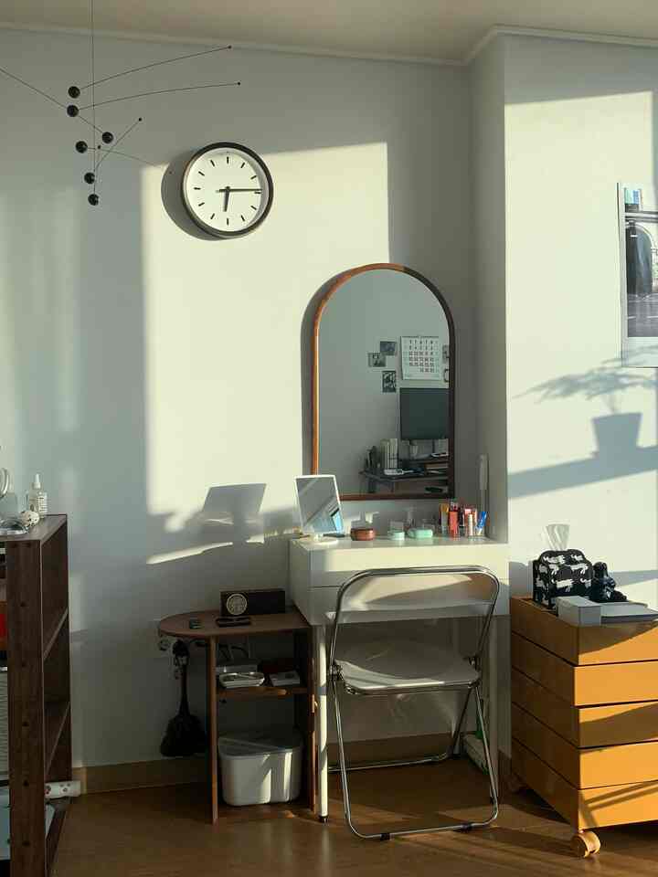 暖かい日差しが差し込む、ホワイトとウッドトーンのワンルームの化粧台空間