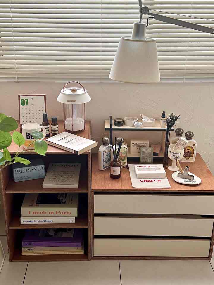 A cozy bedroom featuring white and wood tone shelves and cabinets with a prominent table lamp