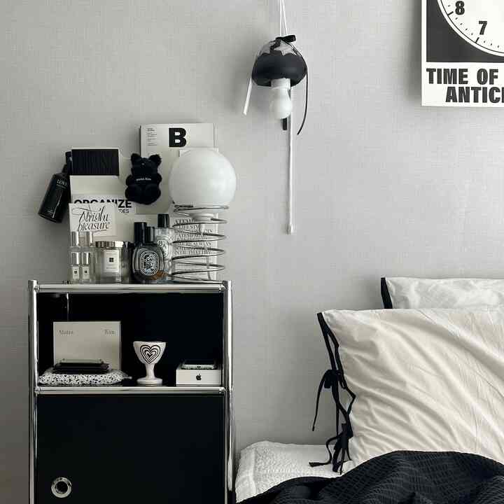 Black and white toned bedroom featuring bed, nightstand with accessories, creating a clean modern atmosphere