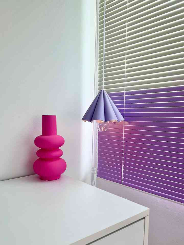 Kids' room corner with white cabinet featuring a pink objet and purple-toned blinds creating a calm atmosphere