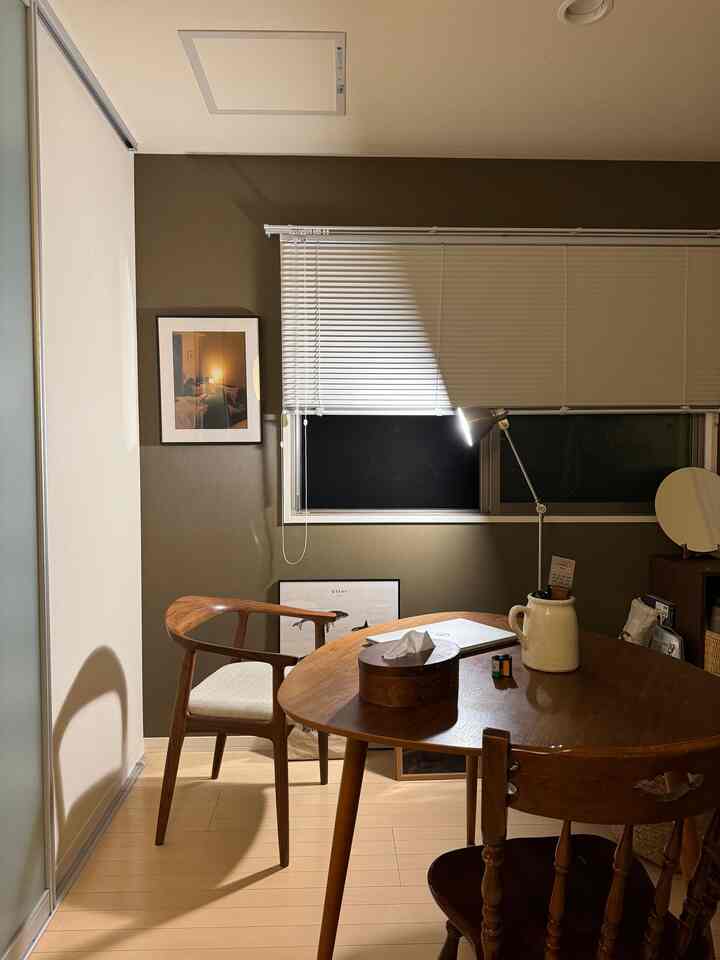 温かみのあるナチュラルカラーのダイニング、木製のテーブルと椅子、白いブラインドとフロアランプが配置された雰囲気のあるインテリア