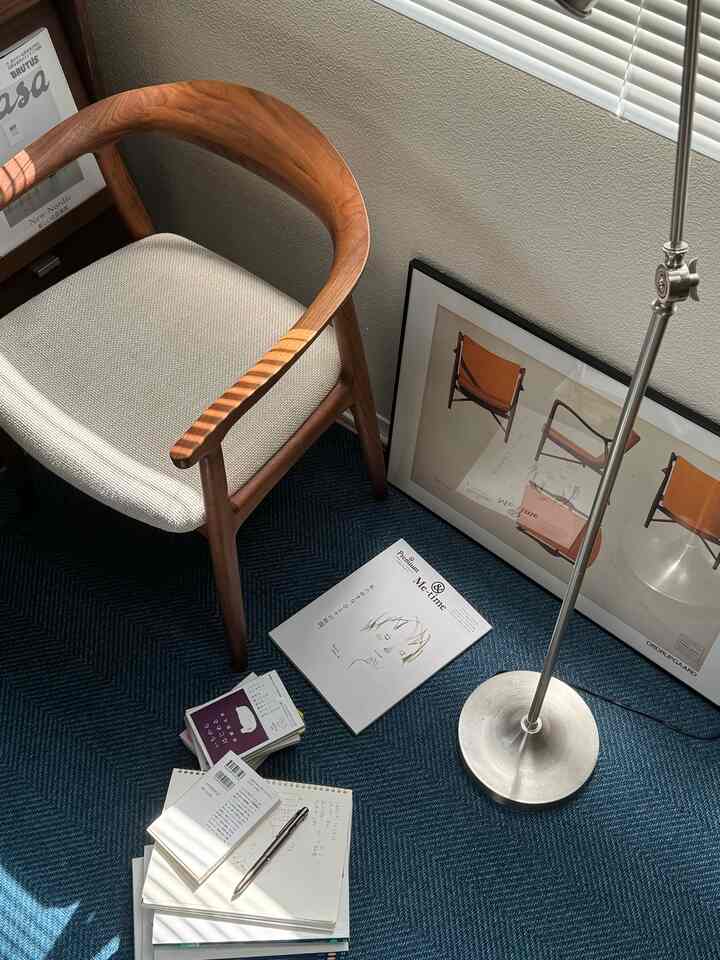 Compact study space featuring a wood tone armchair, blue rug, and a silver floor lamp with natural light