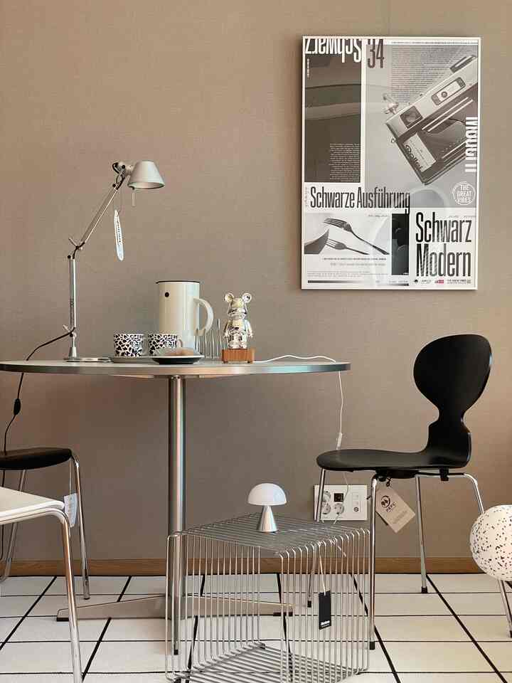 Beige-toned wall with metallic round table and modern black dining chair in a Scandinavian style dining space