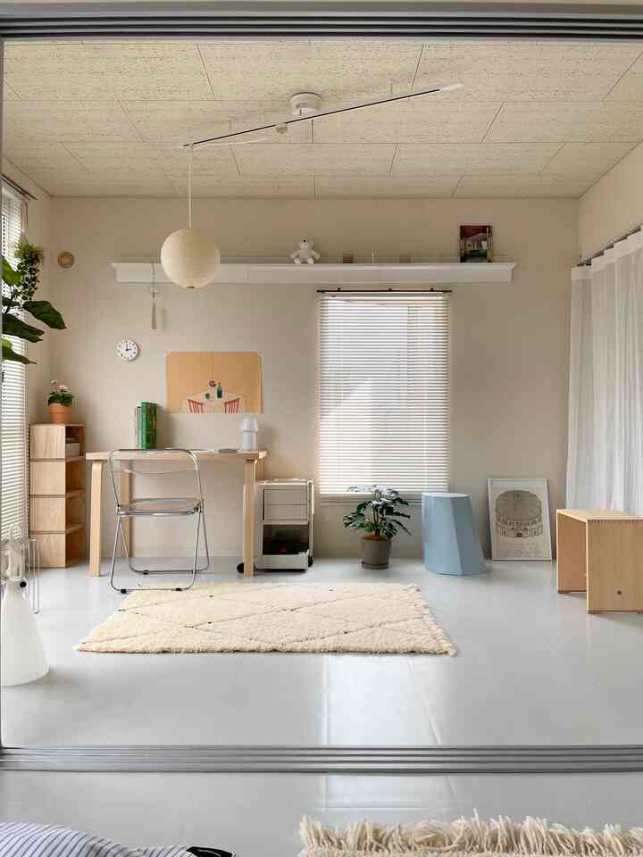 Natural-toned compact workspace featuring a transparent chair and stool in a clean setting
