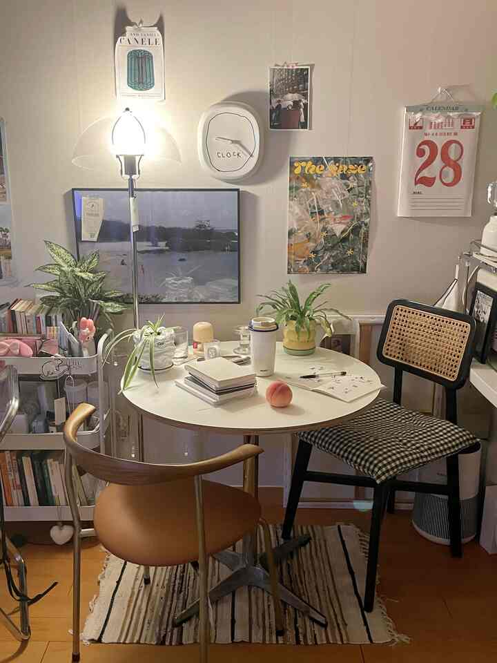 柔らかい白を基調とした小さなホームカフェ空間、丸テーブルと異なる椅子、植物、照明が雰囲気あるインテリアを演出。
