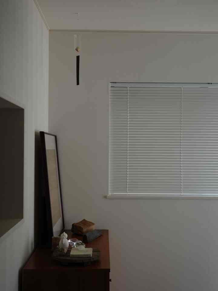 白と木目調の玄関または小さな空間、ミニマルな木製キャビネットとシンプルな装飾が配置された落ち着いた雰囲気のインテリア